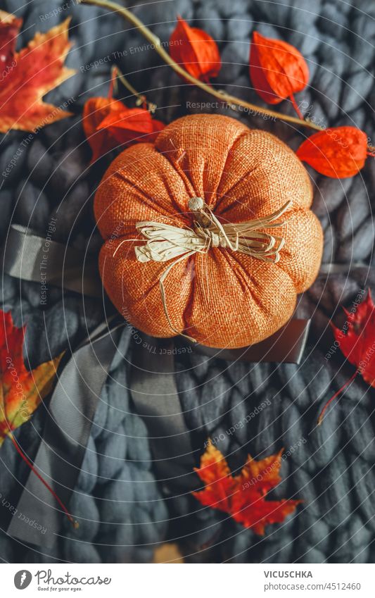 Orange textile pumpkin on dark grey wool blanket with autumn leaves. Cozy home with fall decoration. Top view. orange cozy top view background beautiful