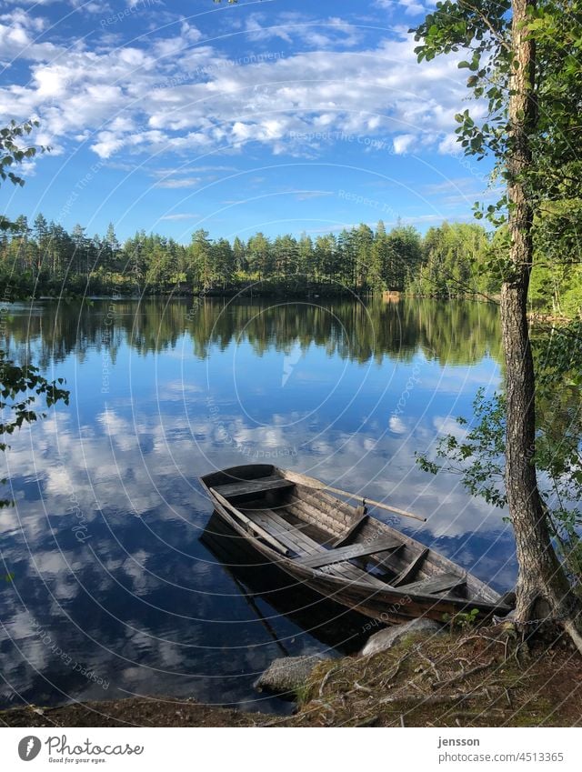 Rowing boat at a lake in Sweden Scandinavia Lake Summer Lakeside Summer vacation Summery Blue sky blue sky with clouds Reflection in the water Rowboat