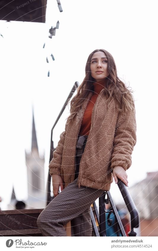 Fashion style portrait. beautiful stylish girl with long hair walks in the city. Portrait of attractive girl on the street. Spring or fall day. selective focus.