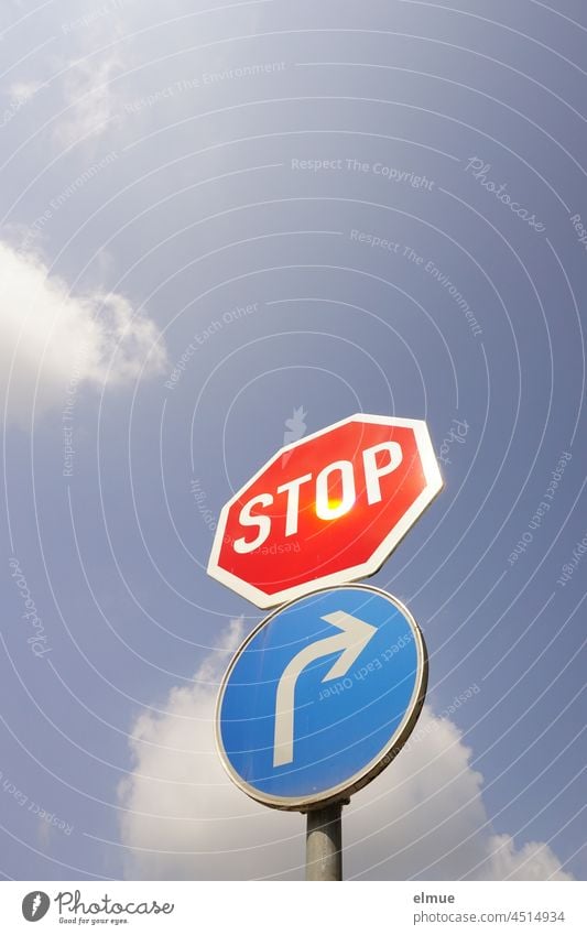 Signs I Traffic sign stop and prescribed driving direction to the right in front of a blue sky with clouds from the frog perspective / VZ 206 and VZ 209-20