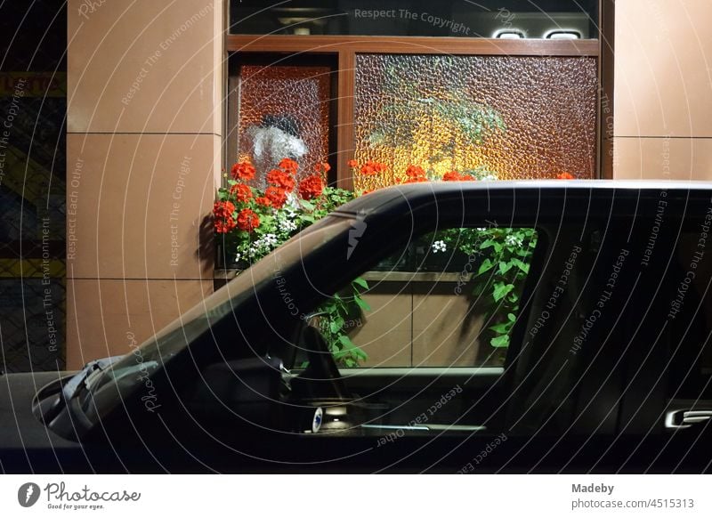 Noble black off-road vehicle in front of a traditional illuminated inn at night in Berger Straße in the Bornheim district of Frankfurt am Main in the German state of Hesse