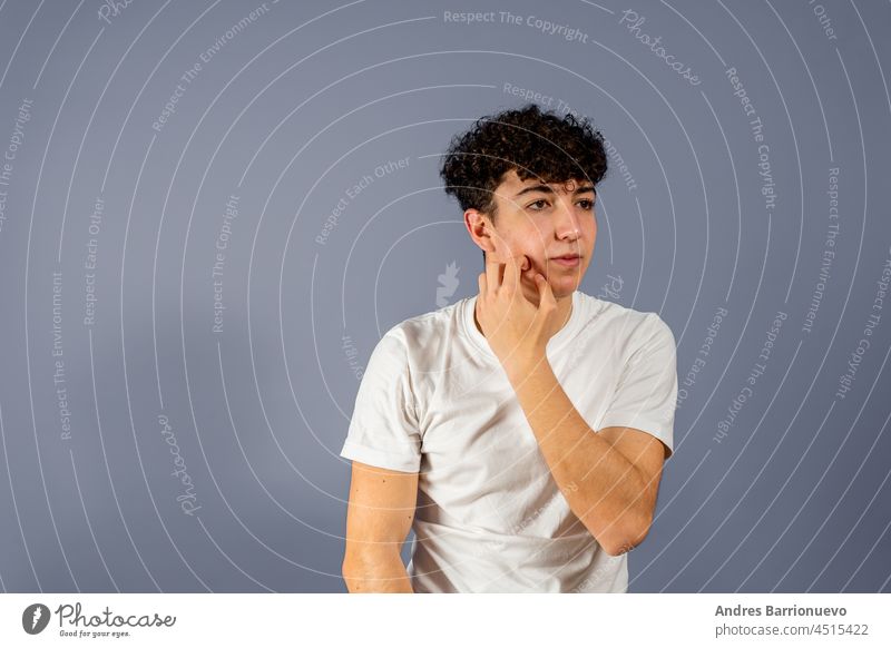 Portrait of the young thinking man looks up with hand near face - isolated on gray. white background male adult portrait thoughtful caucasian studio pensive guy