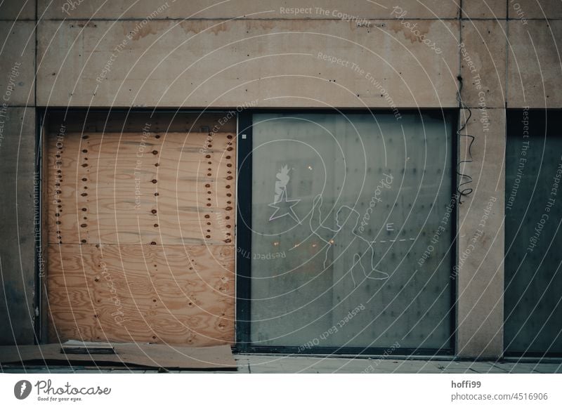 Drab exposed concrete structure with wooden nailed gate and inserted sliding glass door - construction site Construction site Goal Facade Gloomy Gray Concrete