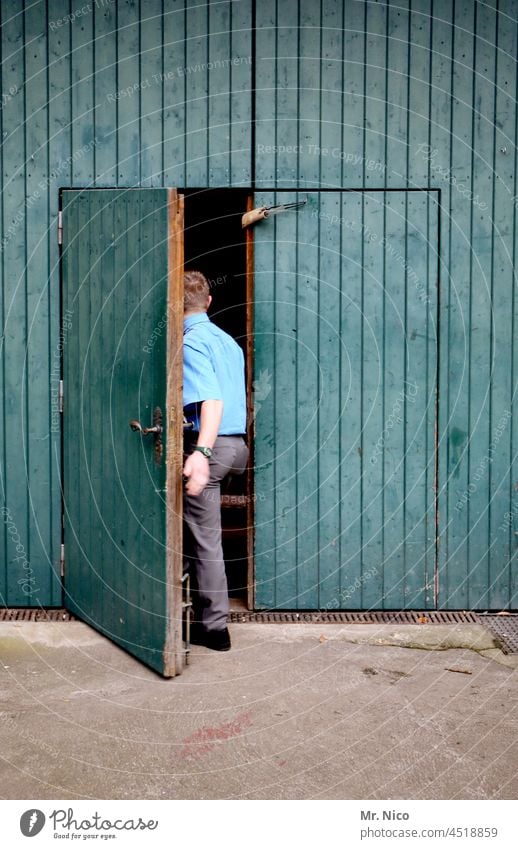 A man opens a wooden door and enters a shed Goal Wooden door Wooden gate Entrance Way out Front door Main gate Open go in Flake Barn Barn door Storage shed Old