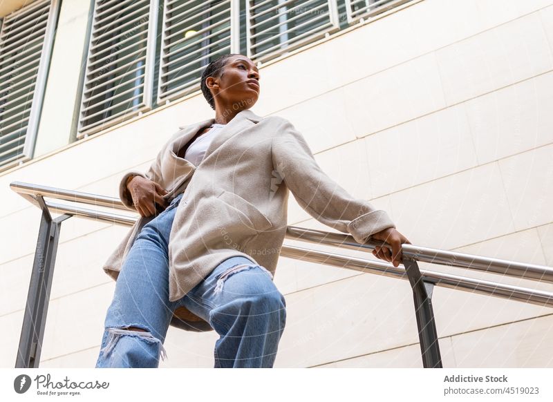 Stylish black woman near railing style street trendy outfit city building attire urban garment handrail african american female lady modern short hair