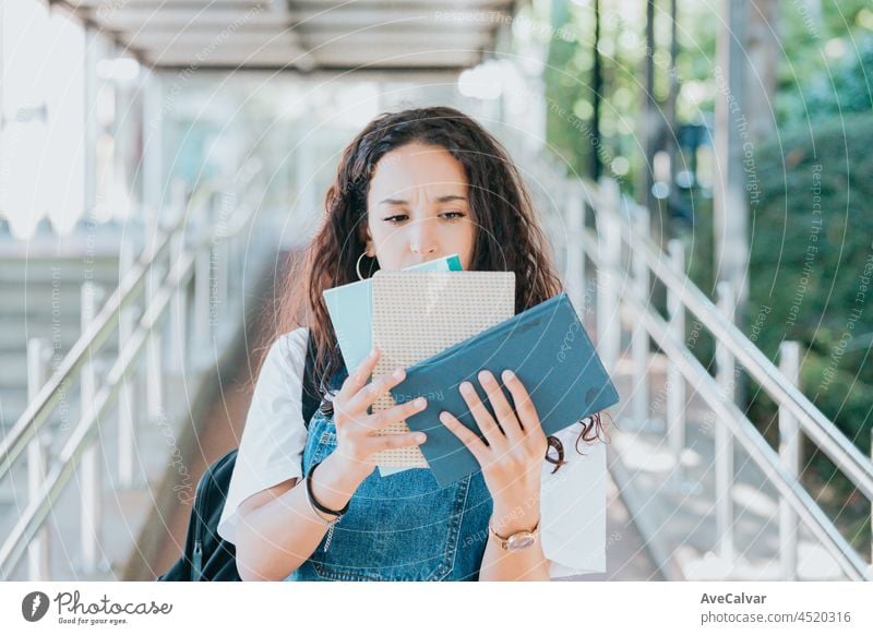 Young student girl, worried holding a bunch of books while going to class in the university, hipster style, studying concept, books and bag education african