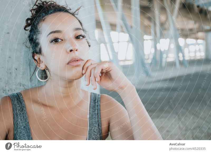 Young african woman looking serious to camera during a exercise session in the city, urban style image, sport and activities in the city, copy space young