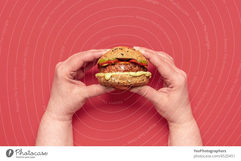 Vegan burger above view on a red table. Woman holding a veggie burger. alternative background bread breakfast cheese cheeseburger color consumerism cuisine