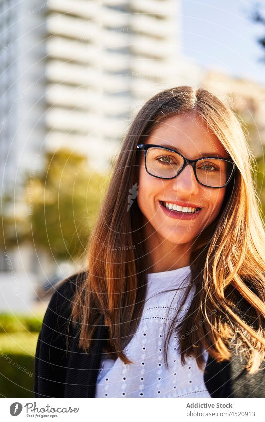 Happy woman standing on park near residential buildings district street cheerful smile positive plant female city urban green joy happy daytime toothy smile