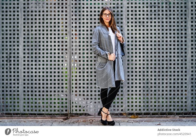 Smiling woman in formal wear standing near fence worker confident well dressed posture individuality appearance style positive professional female businesswoman