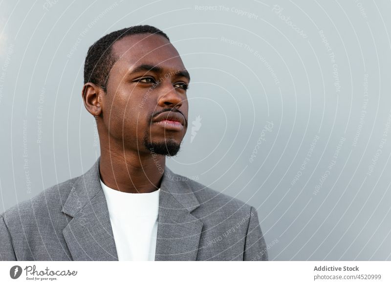 Black man in formal outfit standing near gray wall businessman elegant respectable portrait professional appearance style well dressed suit male entrepreneur