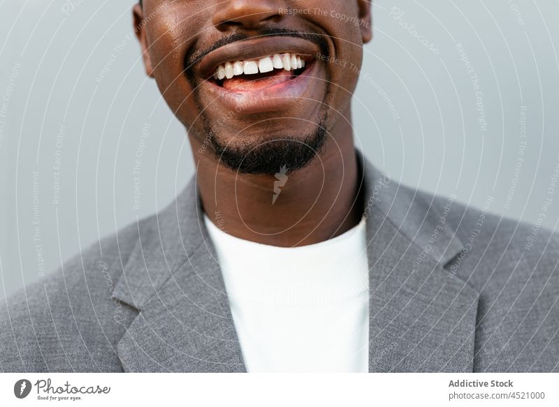 Positive black man in formal outfit standing near gray wall businessman positive elegant respectable portrait professional appearance style well dressed suit