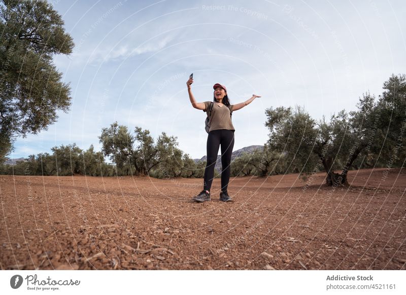 Cheerful Asian woman taking selfie in olive grove smartphone tree plantation photography capture countryside farmland gadget mobile device summer green positive