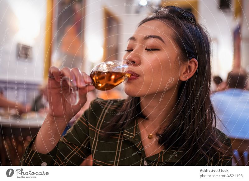 Asian woman drinking alcohol drink restaurant booze chinese beverage wineglass aperitif taste flavor attractive lady female leisure black hair dark hair