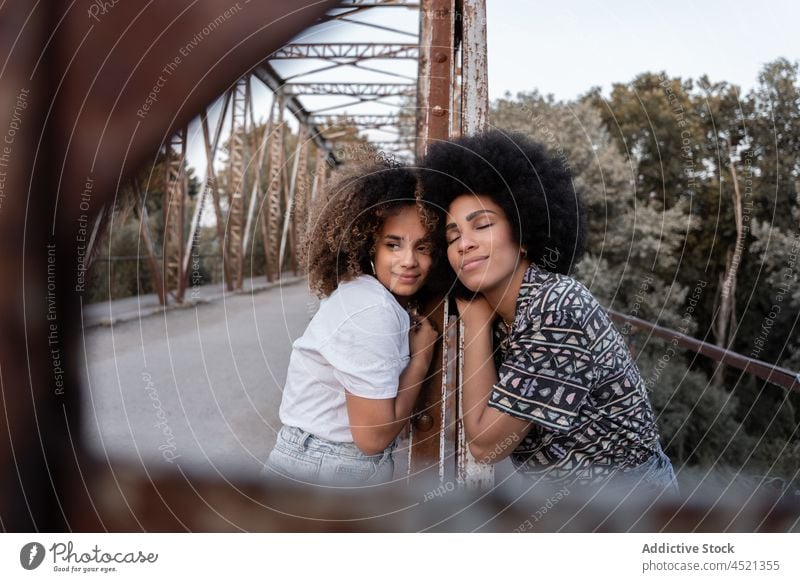 Black friends caressing on old bridge women gentle bonding tender shabby harmony carefree female together girlfriend curly hair pleasant brunette serene nature