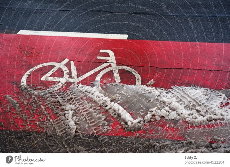 Bike lane with red pavement markings in winter road conditions. Wheel cycle path Street Cycle path Lane markings Direction Asphalt Road marking Clue Snow mud