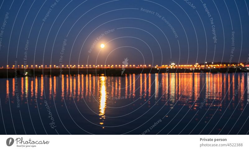 sunset on the coast of the lake. Natural landscape. reflection, night city illumination, blue sky and yellow sunlight. landscape during sunset. background