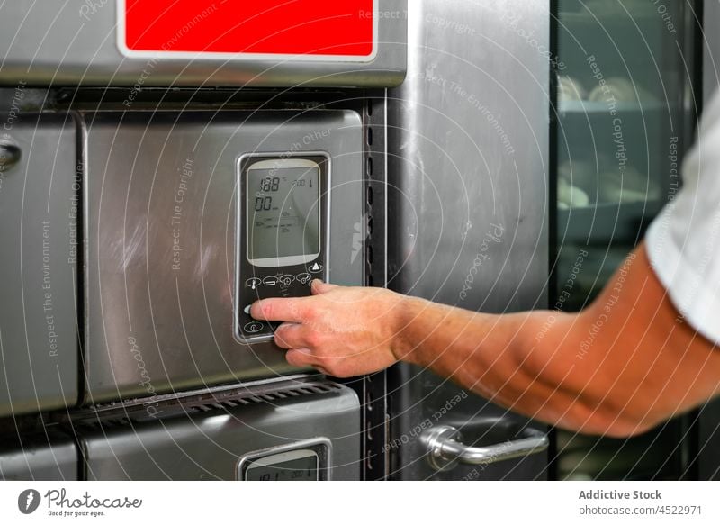 Crop man turning on oven in bakehouse turn on bakery bread pastry button push process prepare kitchen culinary male hand display temperature sweet equipment