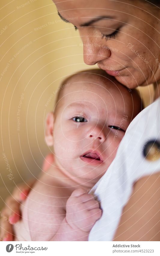 Loving mother hugging newborn at home woman embrace baby caress motherhood babyhood love tender together affection female young stroke calm parent mom harmony