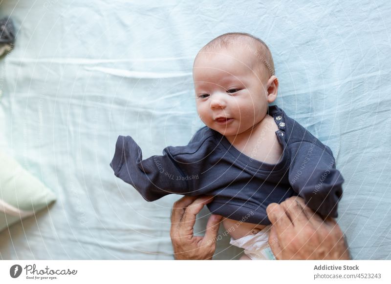 Crop dad dressing newborn on bed baby man father put on caress childcare bedroom lying innocent parenthood cute change bodysuit daylight diaper adorable