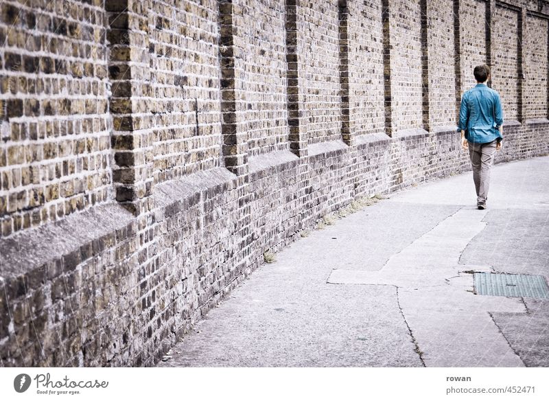 upright Human being Masculine Young man Youth (Young adults) Man Adults 1 Going Brick Brick wall Stride Step-by-step Upright gait Shirt Blue Curve Sidewalk