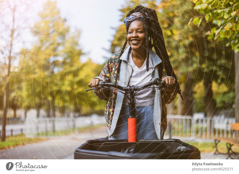 Woman using cargo bike in urban area unaltered natural real people authentic body inclusivity body positive one person hipster girl hairstyle dreadlocks