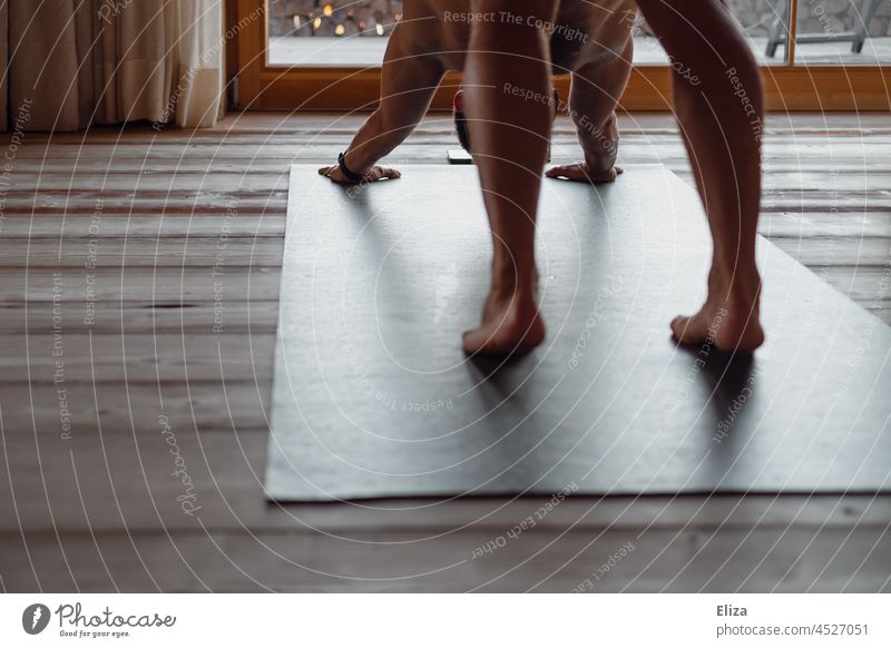 A man does yoga exercises on a yoga mat at home with a course on his phone Yoga Man Naked Lifestyle Cellphone Telephone Fitness wooden floor Black Yoga posture