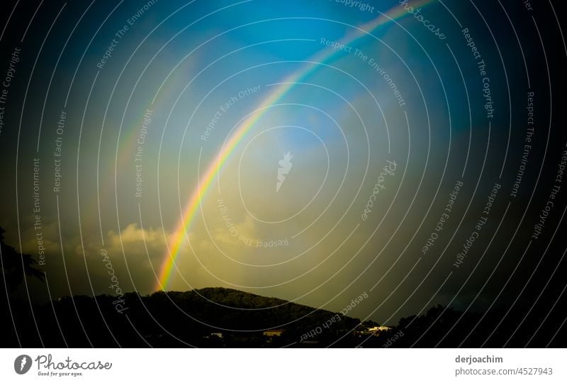 After a rain shower, a beautiful rainbow spectacle appears on the hills. A small piece of the blue sky is also already visible. Rainbow Multicoloured Colour