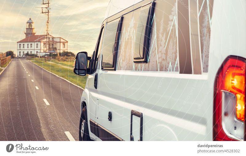 Closeup of camper van traveling to a lighthouse road nobody vacation campervan autumn mobile home cloudy landscape freedom sightseeing leisure trip vehicle