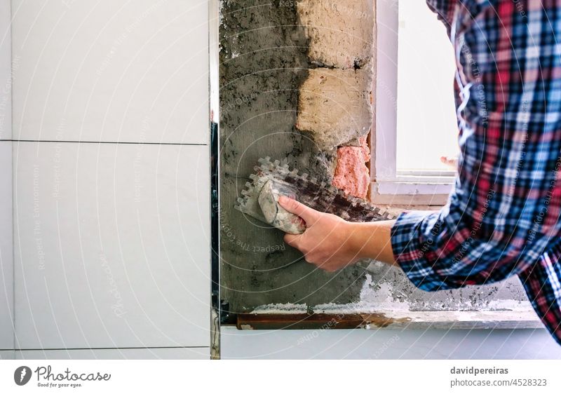 Female bricklayer leveling cement with a trowel unrecognizable mason hand concrete wall tile bathroom closeup masonry copy space construction female arm woman