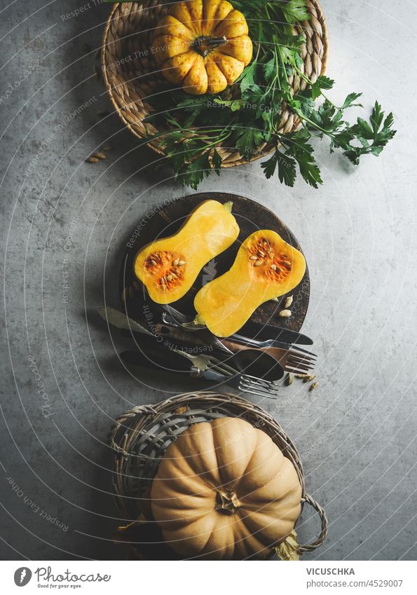 Halve of butternut squash on pale grey kitchen table with millet in bowl and kitchen utensils. Preparing healthy vegan millet porridge at home with seasonal autumn ingredients. Top view.