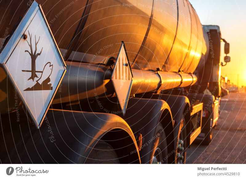 Contamination hazard labels on a tanker truck for the transport of dangerous goods. tank truck hazardous sunset trailer adr rear view trucking fuel environment