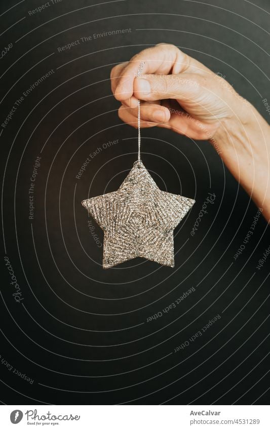 Female hands holding new year merry christmas silver star, props and accessories, golden and red christmas tree balls, dark background no people creativity