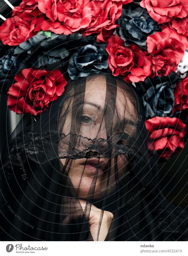 a woman of Caucasian appearance is dressed in a black veil and a large wreath of red-black roses beauty flower beautiful hair portrait female fashion art model