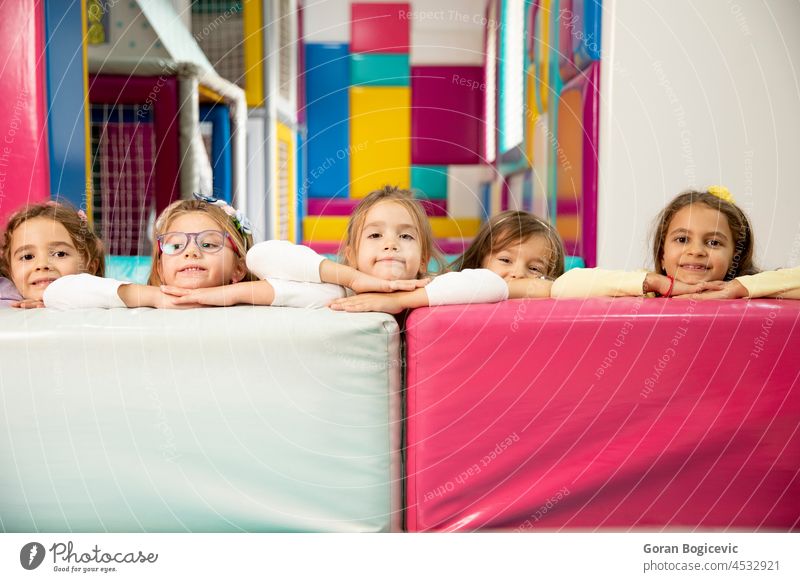 Group of cute little girls hiding behind large leather blocks happy group smiling friends preschool child kindergarten together childhood people preschooler