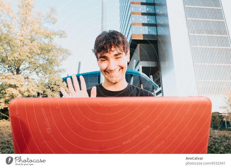 Portrait of a young business student guy in a black shirt using the laptop doing a video call in an outdoor, notebook student business concept, modern design business buildings