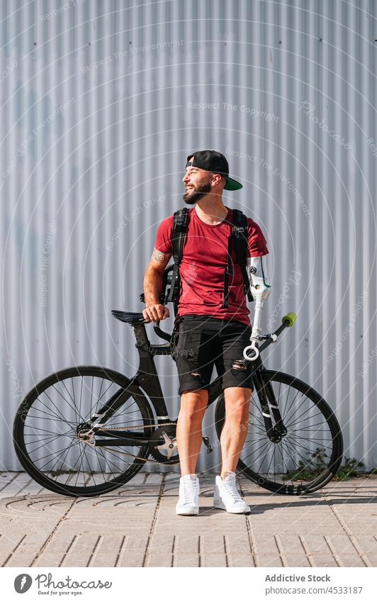 Cheerful man with arm prosthesis in street artificial limb smile prosthetic hipster bike city male handicap happy looking away glad cheerful bicycle trendy cool