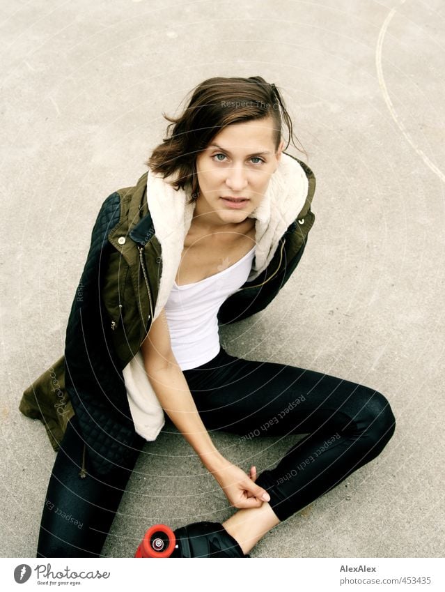 Portrait of a young athletic woman with roller skates sitting on a concrete floor Fitness Leisure and hobbies Playing Inline skating Skate park Young woman