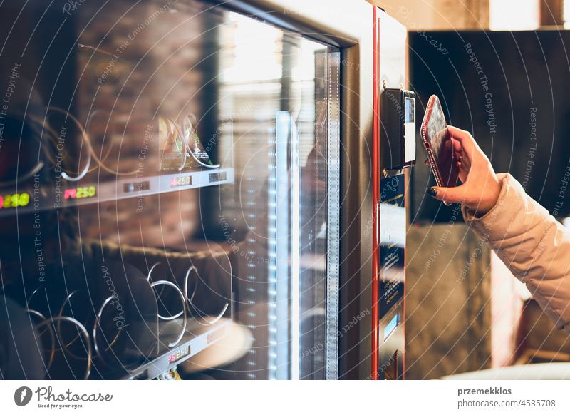 Woman paying for product at vending machine using smartphone buying contactless payment goods consumer wireless woman technology person money automatic