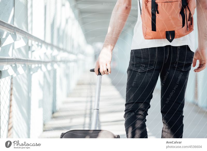 Back shot of a traveler carrying his luggage and bags at the airport or bus station during a travel. Hipster modern traveler, sunny day, copy space. baggage man