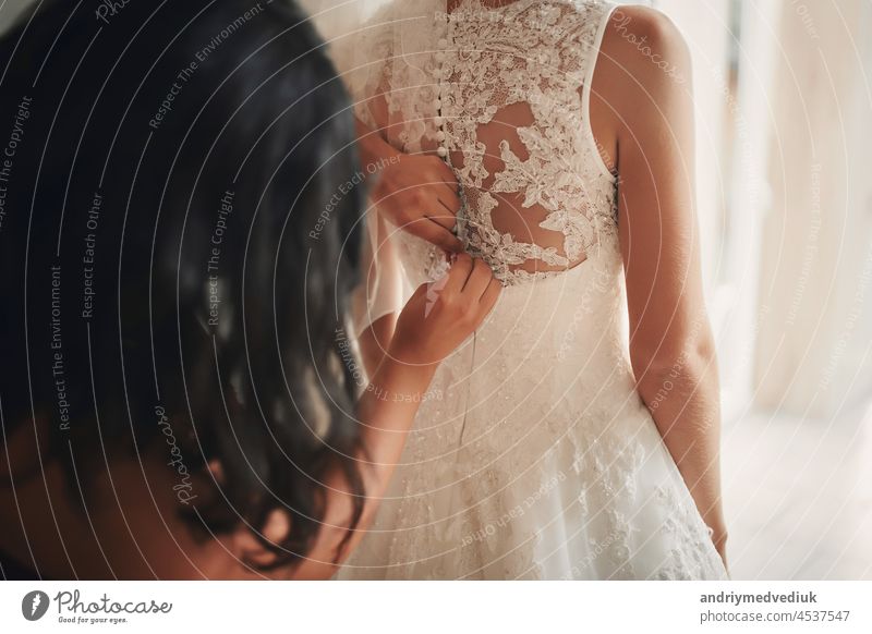 Bridesmaid helping bride fasten corset close-up and getting her dress, preparation concept in morning for wedding ceremony. luxury bridesmaid white woman