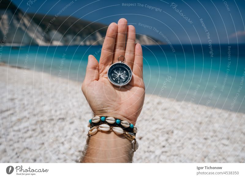 Hand holding a compass on the beach in background hand sea vacation travel equipment lost journey summer east hiking exploration direction guidance ocean