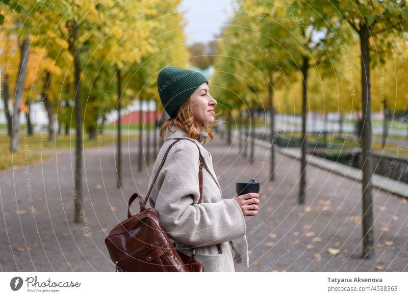 Woman drinking from reusable cup at autumn park woman fall environmental conservation female adult lifestyle person outdoor nature mug one person relaxation