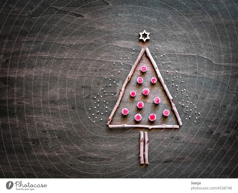 Ein Christbaum aus Ästen und kleinen roten Kugeln auf einem Holztisch Weihnachten Weihnachtsbaum Advent Winter Ast kugel basteln holztisch abstrakt draufsicht