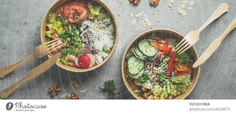 Japans poke bowl with seafood and salad and vegan bowl with vegetables and chickpeas in sustainable food container at grey background. Eco-friendly delivery food with plastic free cutlery. Top view.