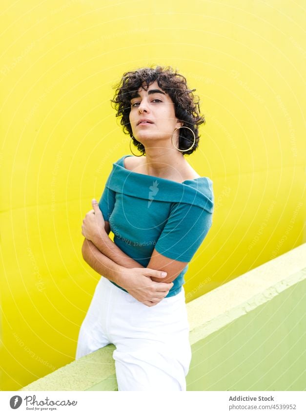 Confident woman sitting on wall near bright background gaze personality appearance confident self assured colorful elegant posture individuality female style