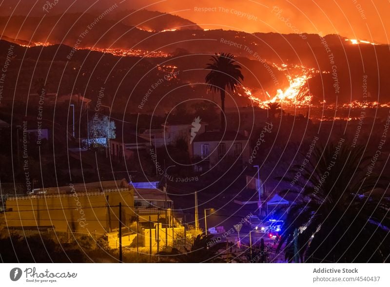 Orange lava flowing in mountainous terrain after volcano eruption in Spain house residential magma cliff landscape nature night scenery burn picturesque danger