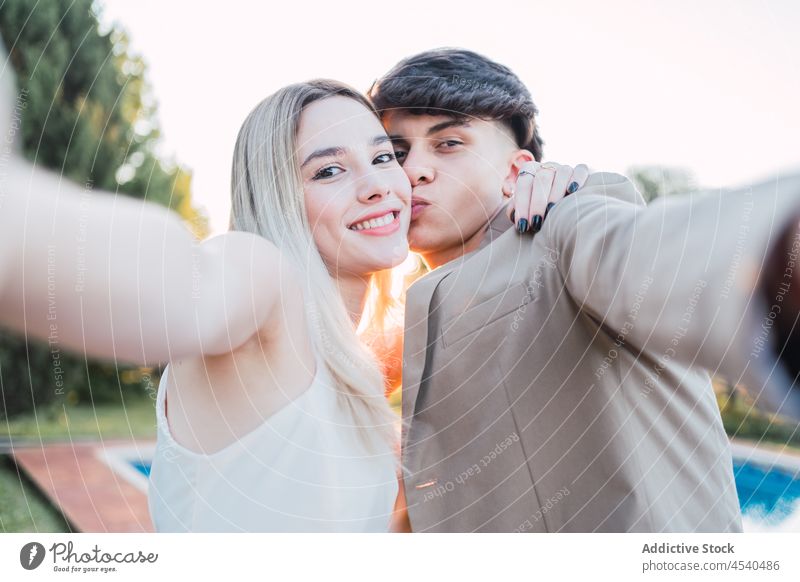 Glad couple taking selfie on poolside cheerful smartphone cellphone using carefree self portrait together love chill relax summer gadget resort enjoy kiss rest