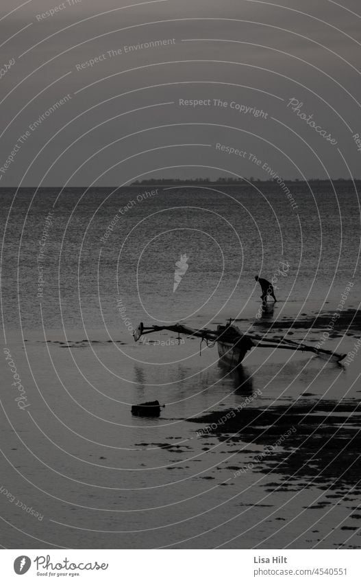 Man and boat in the water at low tide. Black and white photo. black and white photo Low tide Water Calm mythical Fog Golden section Dark White B/W Loneliness