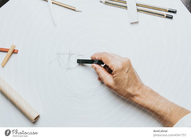 High angle view of a senior Caucasian woman drawing sketches in studio. Creativity, education and people concept,cognitive functions clock drawing self assessment test at home with positive results